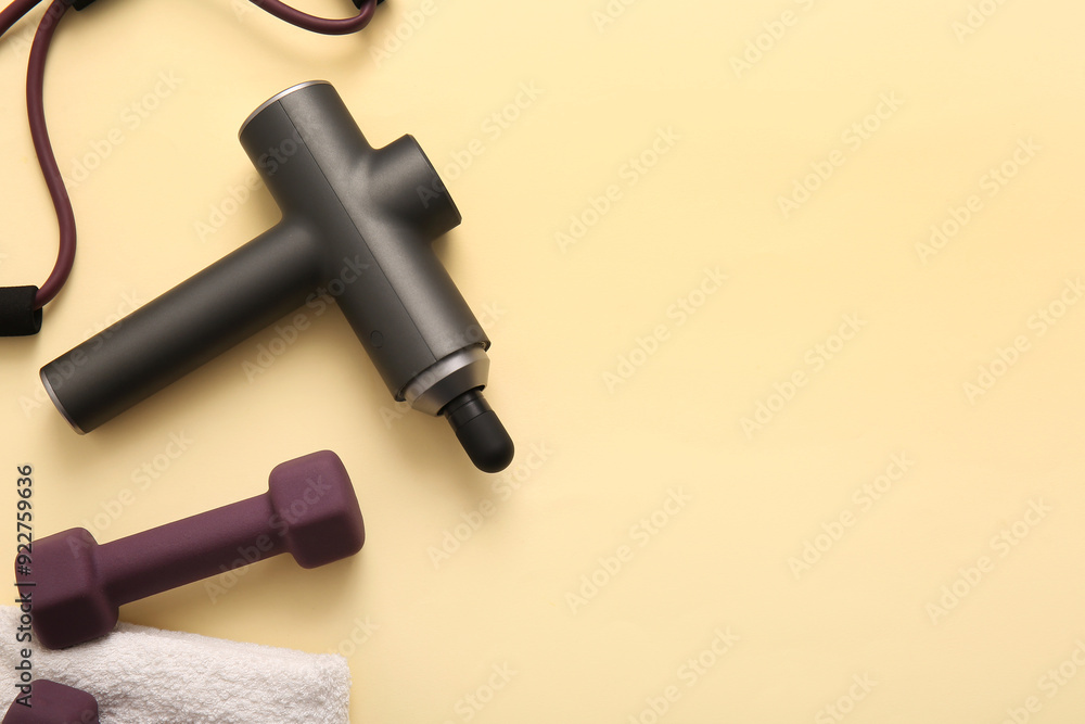 Percussive massager, dumbbells and expander on color background Percussive massager, dumbbells and expander on color background