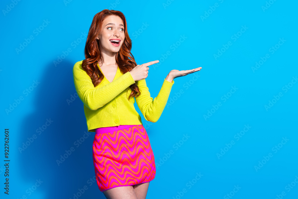 Photo portrait of attractive young woman point hold look empty space dressed stylish yellow clothes isolated on blue color background Photo portrait of attractive young woman point hold look empty space dressed stylish yellow clothes isolated on blue color background