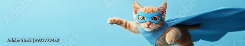 Feline Heroics: A Playful Orange Tabby Cat in a Blue Cape and Mask, Soaring on a Light Blue Background, Embracing the Superhero Concept. photo