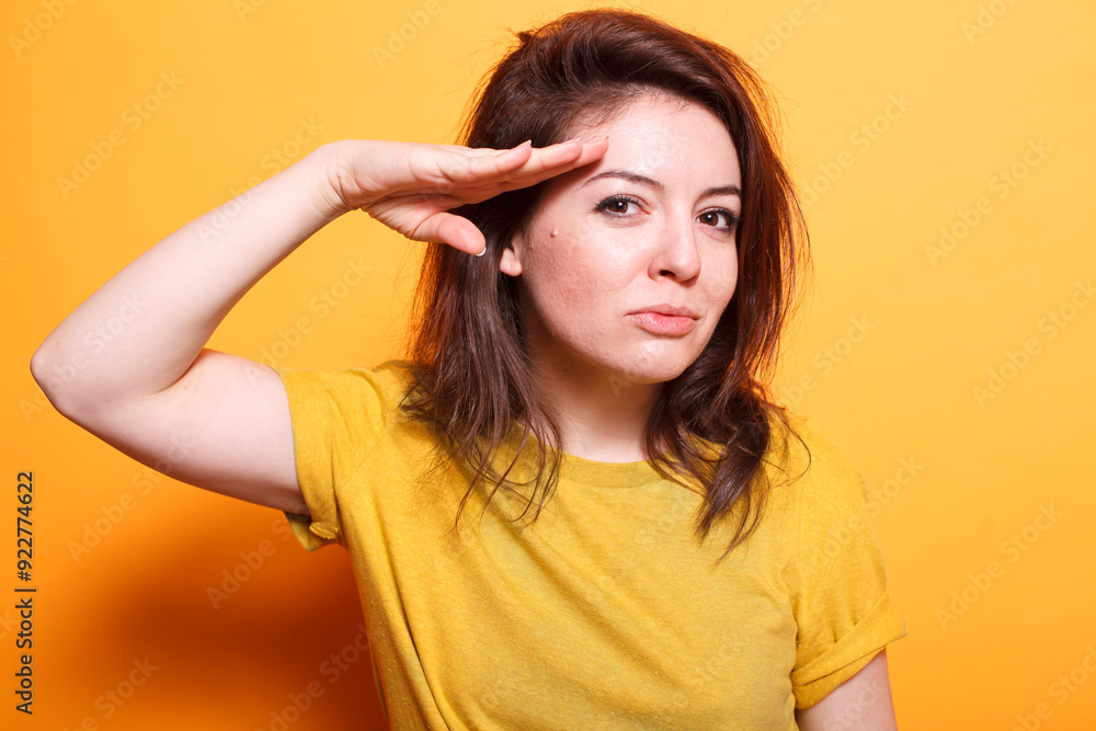 Portrait of woman giving a military salute in front of the camera, feeling confident and joyful. Close-up of caucasian person posing with their hand at their forehead to show respect. Portrait of woman giving a military salute in front of the camera, feeling confident and joyful. Close-up of caucasian person posing with their hand at their forehead to show respect.