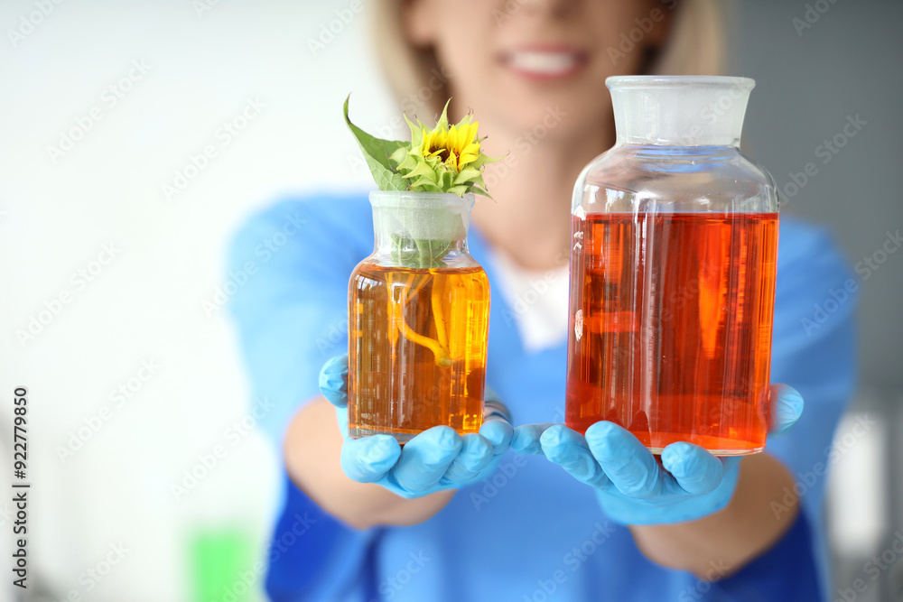 Happy female scientist with flasks of samples and sunflower in laboratory, closeup Happy female scientist with flasks of samples and sunflower in laboratory, closeup