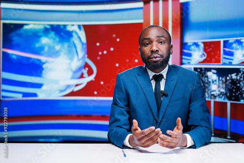 News anchor man reading media papers, transmitting live information from exclusive sources to create latest news report. African american journalist presenting daily events and important topics. photo