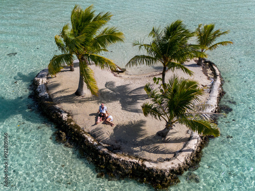 Aerial view from drone of a happy couple together on a small tropical island. The romantic vacation is on a heart shaped motu.  photo