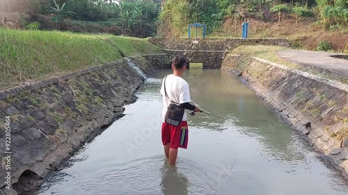 a man who was doing his fishing hobby using casting techniques in a river in the Magelang area, Central Java, Indonesia photo