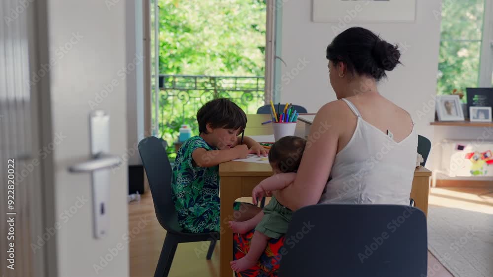 Mother sits with her children during a homeschooling session at the table, candid educational activities while the mother cradles the baby, portraying a serene family moment Mother sits with her children during a homeschooling session at the table, candid educational activities while the mother cradles the baby, portraying a serene family moment