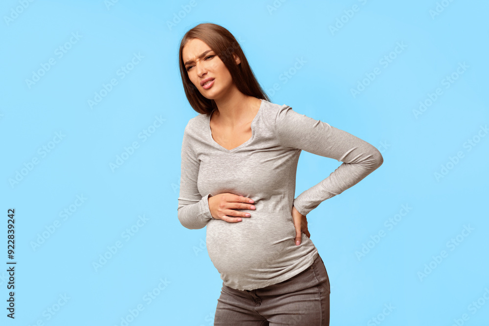 Backache. Pregnant Lady Suffering From Lower Back Pain Standing Over Gray Studio Background. Free Space Backache. Pregnant Lady Suffering From Lower Back Pain Standing Over Gray Studio Background. Free Space