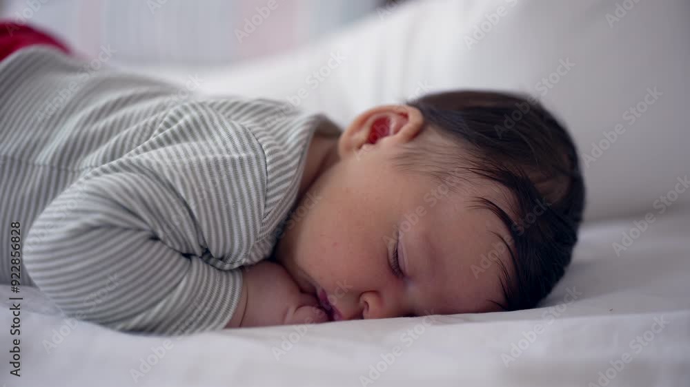 Newborn baby peacefully sleeping on a bed, dressed in a striped onesie, capturing a serene and restful moment of early life in a cozy home environment Newborn baby peacefully sleeping on a bed, dressed in a striped onesie, capturing a serene and restful moment of early life in a cozy home environment