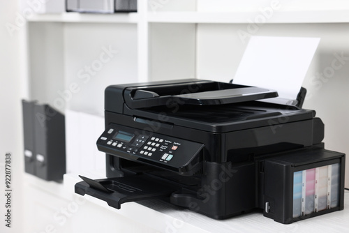 Modern printer with paper on table in office