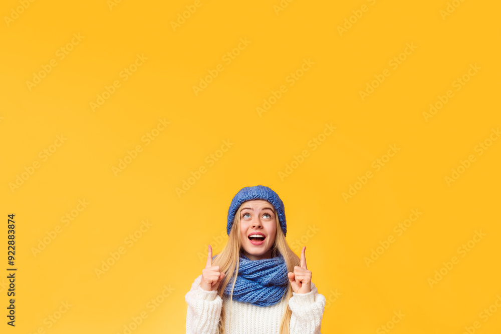 Amazed girl in blue winter hat pointing up at copy space over pink background Amazed girl in blue winter hat pointing up at copy space over pink background