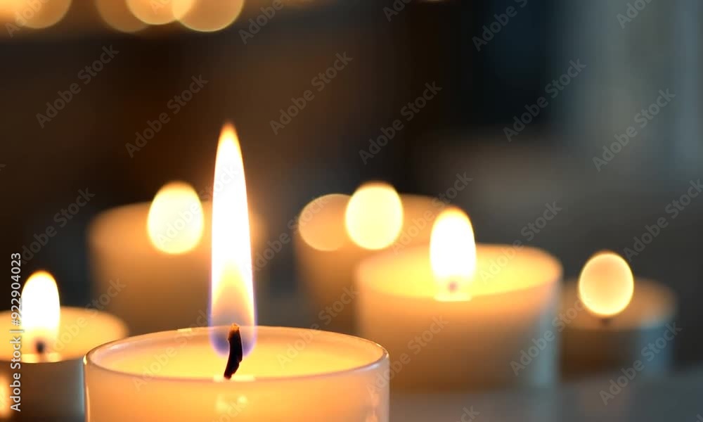 Closeup of a lit candle with a blurry background of other candles. Closeup of a lit candle with a blurry background of other candles.