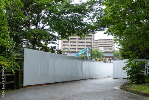 Obraz na plátně Long, empty blank white construction barriers or fence walls made up of several panels joined together, for temporary work sites in a park