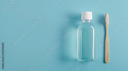 Plastic bottle with mouthwash, wooden toothbrush on blue background