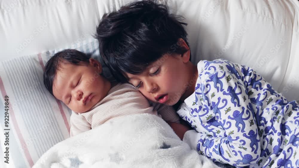 Sibling love depicted as young boy sleeps next to newborn sibling, both snuggled together under blanket, creating heartwarming and tender family moment in calm bedroom Sibling love depicted as young boy sleeps next to newborn sibling, both snuggled together under blanket, creating heartwarming and tender family moment in calm bedroom