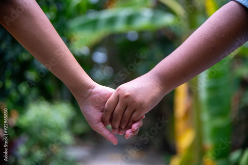 Two children's hands holding hands, close-up, natural light with blurred background.