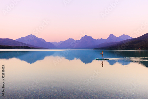 A woman paddle boards on Lake McDonald in Glacier National Park at sunset photo