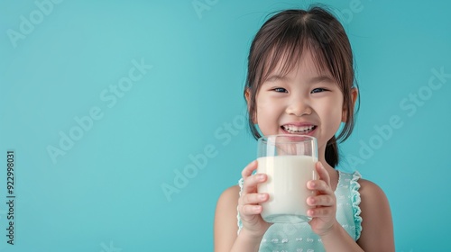 A happy little kid drink milk from glass
