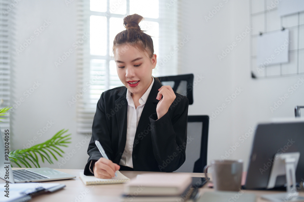 A confident businesswoman in a black suit is sitting at her desk, smiling as she engages in an online meeting, with notes and documents organized on the table in a modern office A confident businesswoman in a black suit is sitting at her desk, smiling as she engages in an online meeting, with notes and documents organized on the table in a modern office