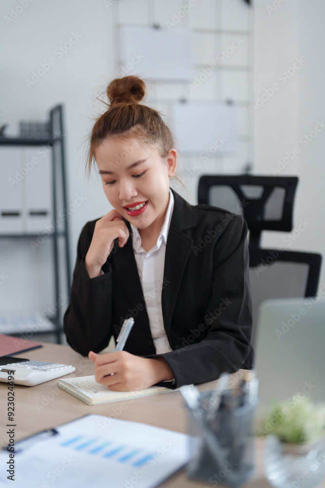 A confident businesswoman in a black suit is sitting at her desk, smiling as she engages in an online meeting, with notes and documents organized on the table in a modern office A confident businesswoman in a black suit is sitting at her desk, smiling as she engages in an online meeting, with notes and documents organized on the table in a modern office