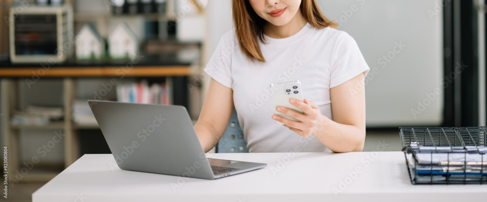 Young woman typing on tablet and laptop while sitting at the working wooden table modern office Young woman typing on tablet and laptop while sitting at the working wooden table modern office