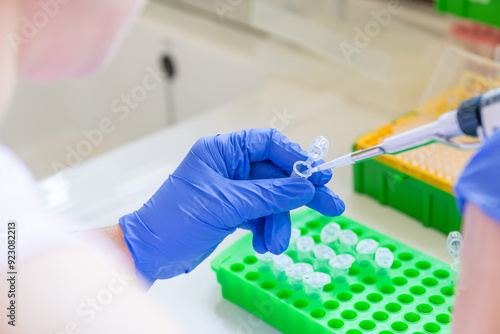 Hand,blue glove holding a micropipette and a eppendorf tube in a laboratory with other equipment. Taking out liquid with pipet from an eppendorf tube. Cardridge for ddPCR on the bench. Dna analysis. photo