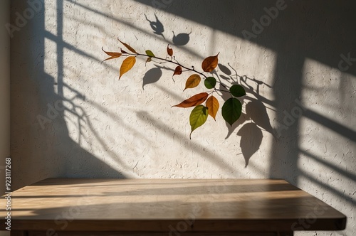 Empty table against beige textured wall background. Composition with glossy leaves on the wall. photo