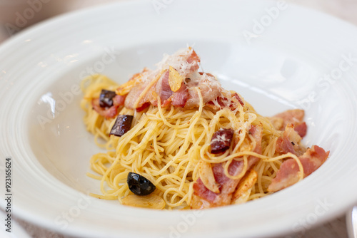 A mouthwatering plate of spaghetti perfectly tossed with dried chili flakes, black olives, and a generous sprinkle of parmesan cheese.