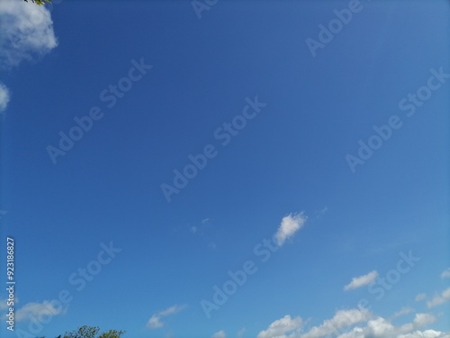 Beautiful clear blue sky background with soft white clouds on a sunny day