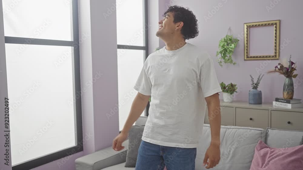 A cheerful young hispanic man stretching with a smile in a stylish living room. A cheerful young hispanic man stretching with a smile in a stylish living room.