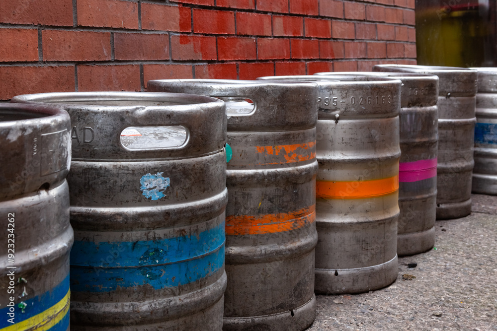 A row of beer barrels outdoors in an alleyway. A row of beer barrels outdoors in an alleyway.