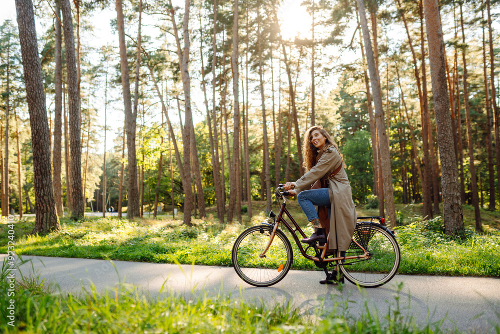 Fototapeta premium Beautiful happy woman riding bicycle in park. Woman enjoys nature. Active day.