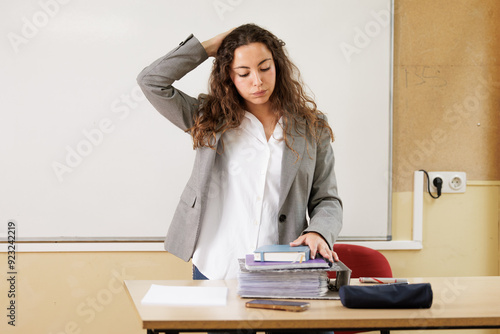 woman overwhelmed by work overload at the table in her office or high school classroom.