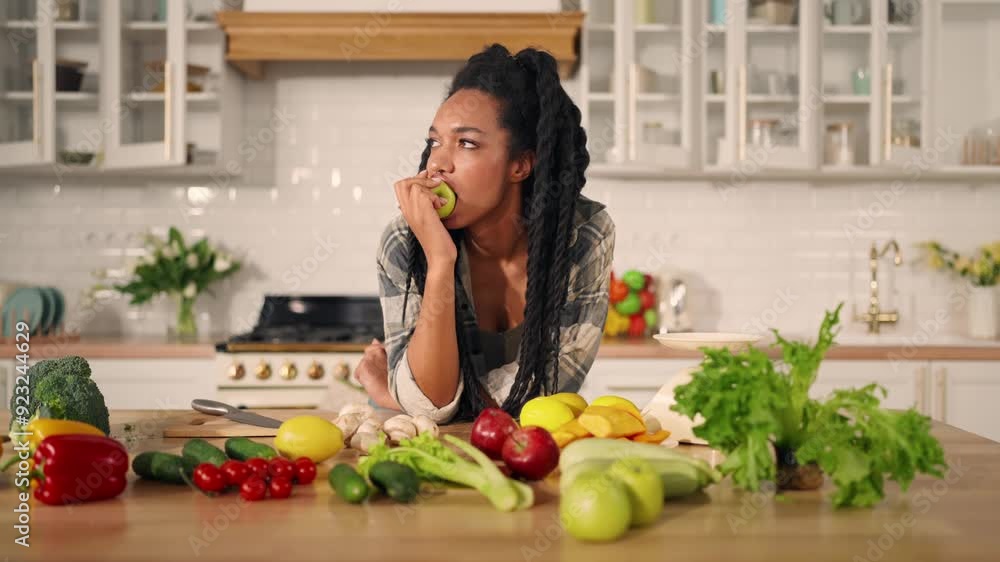 Raw food diet, young black woman biting juicy apple, portrait in kitchen. Healthy nutrition for stay fit and slender, African American lady with dreadlocks eating fruits, table with organic vegetables Raw food diet, young black woman biting juicy apple, portrait in kitchen. Healthy nutrition for stay fit and slender, African American lady with dreadlocks eating fruits, table with organic vegetables