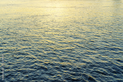 The texture of ripples on the water in a pond illuminated by the setting sun. Natural background.