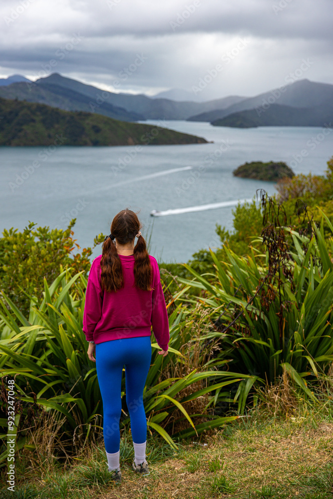 hiker girl enjoys the panorama of picton coastline, new zealand south island; beautiful green hills, small bays and little island; the view from the bobs bay reserve, snout track hiker girl enjoys the panorama of picton coastline, new zealand south island; beautiful green hills, small bays and little island; the view from the bobs bay reserve, snout track