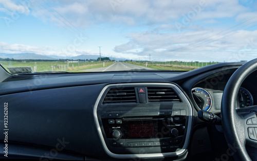 A right hand drive vehicle is being driven along an empty road in New Zealand