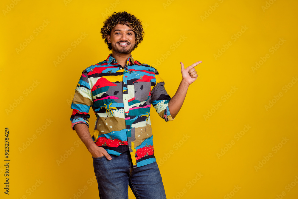 Photo portrait of handsome young male point empty space dressed stylish colorful garment isolated on yellow color background Photo portrait of handsome young male point empty space dressed stylish colorful garment isolated on yellow color background