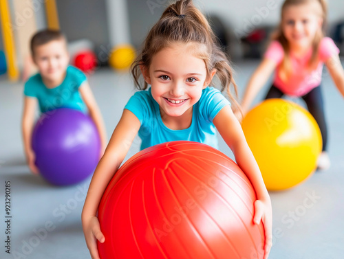 Young girl holding a large red therapy ball during adaptive physical education, active participation in inclusive fitness activities, promoting physical and mental well-being in children