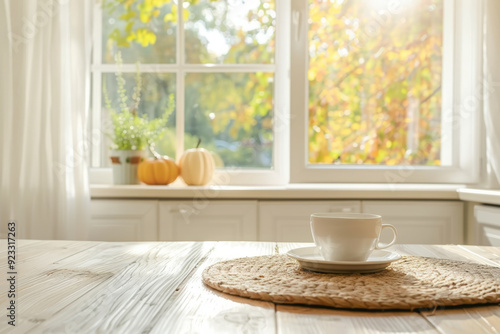 Cozy kitchen interior with a window, a white wooden table, and a cup of coffee on it. Autumn background outside the window. Autumn time concept.
 photo