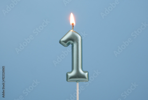 Burning blue birthday candle on blue background, number 1 photo