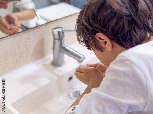 A boy washing his face under running tap