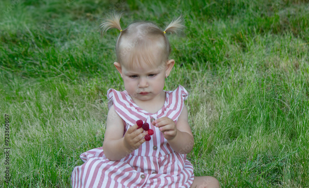 a little girl eats a raspberry. Selective focus a little girl eats a raspberry. Selective focus