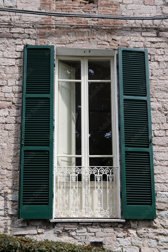 Fototapeta premium View of an old floor-to-ceiling window with a balcony and green shutters
