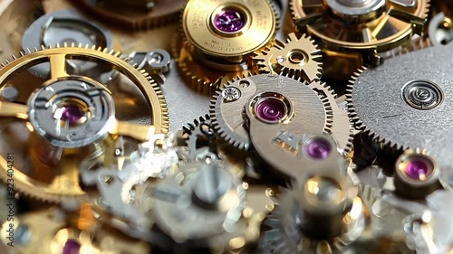 A close up of a watch with the gears visible. The watch is gold and has a pinkish hue