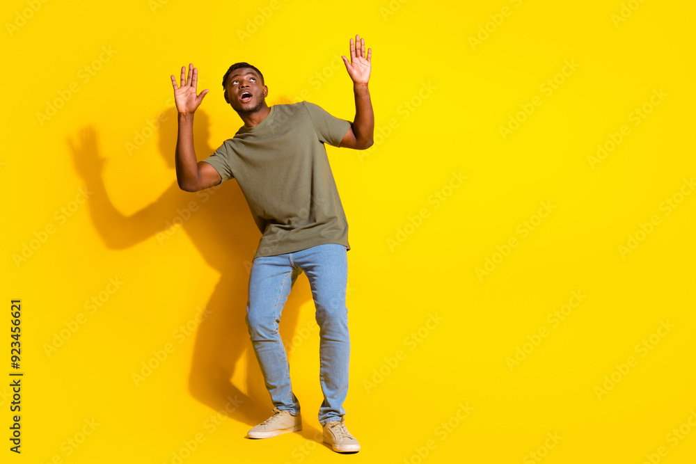 Photo of funny young man wear trendy khaki clothes arm hold empty space isolated on yellow color background Photo of funny young man wear trendy khaki clothes arm hold empty space isolated on yellow color background