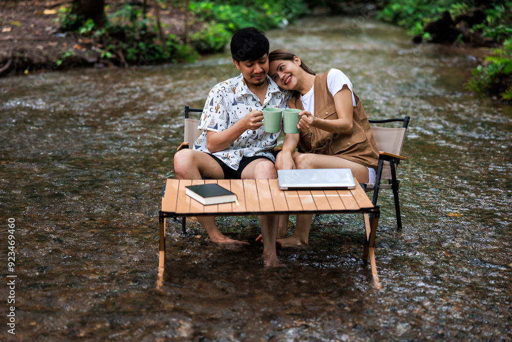 relax and romantic time concept, young asian couple enjoying sitting on wooden chairs drinking coffee together in middle of a stream relax and romantic time concept, young asian couple enjoying sitting on wooden chairs drinking coffee together in middle of a stream