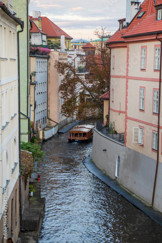 Photography Сruise boat with tourists sailing between buildings on the water canal in Lesser