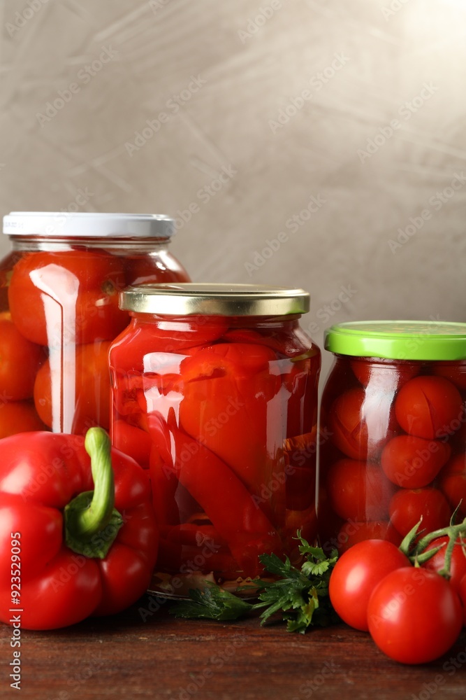 Different pickled vegetables in jars and fresh ingredients on wooden table Different pickled vegetables in jars and fresh ingredients on wooden table