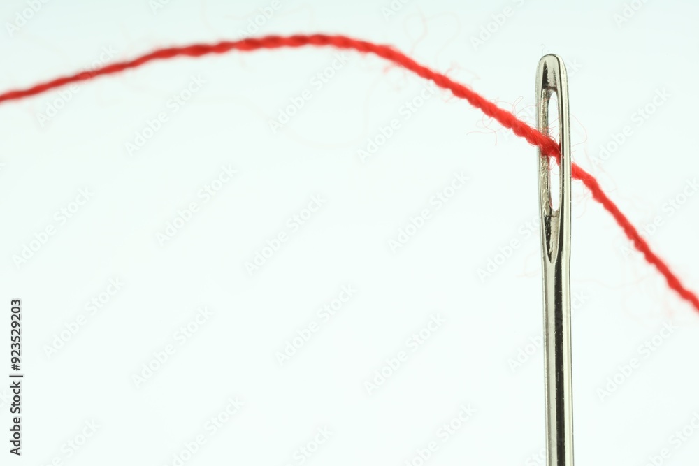 Sewing needle with red thread on white background, closeup Sewing needle with red thread on white background, closeup