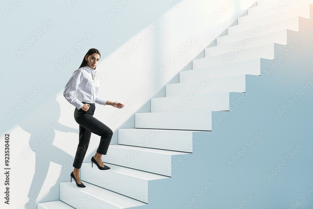 Attractive young businesswoman walking up white stairs and concrete wall. Success, worker, career growth and up concept. Attractive young businesswoman walking up white stairs and concrete wall. Success, worker, career growth and up concept.