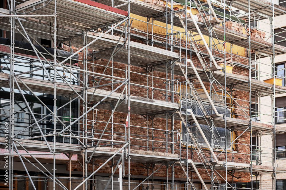 Scaffold for Building Construction. Layher Scaffolding by High rise Building in Construction Site. Scaffold for Building Construction. Layher Scaffolding by High rise Building in Construction Site.
